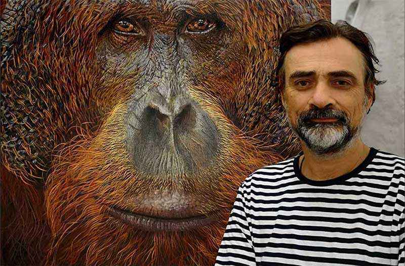 Portrait of the artist next to a canvas of an Orangutan